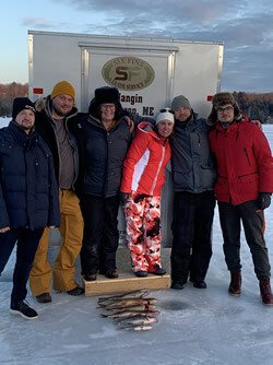 Group photo of six men and women with their combined ice fishing catch.