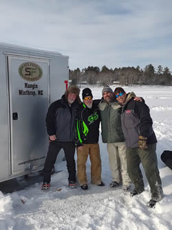 Group photo of four men enjoying ice fishing.
