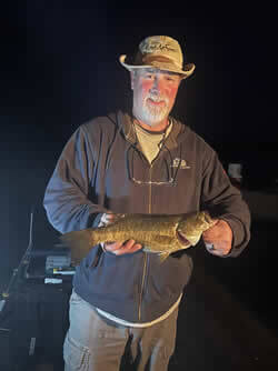 Man holding a Smallmouth Bass he caught during evening open water fishing.