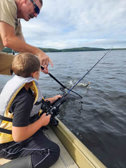 Father and son catching a fish with Six Fins Guide Service.